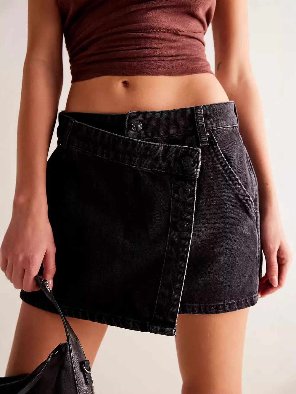 Black asymmetrical button-front denim skort with a wrap detail.
