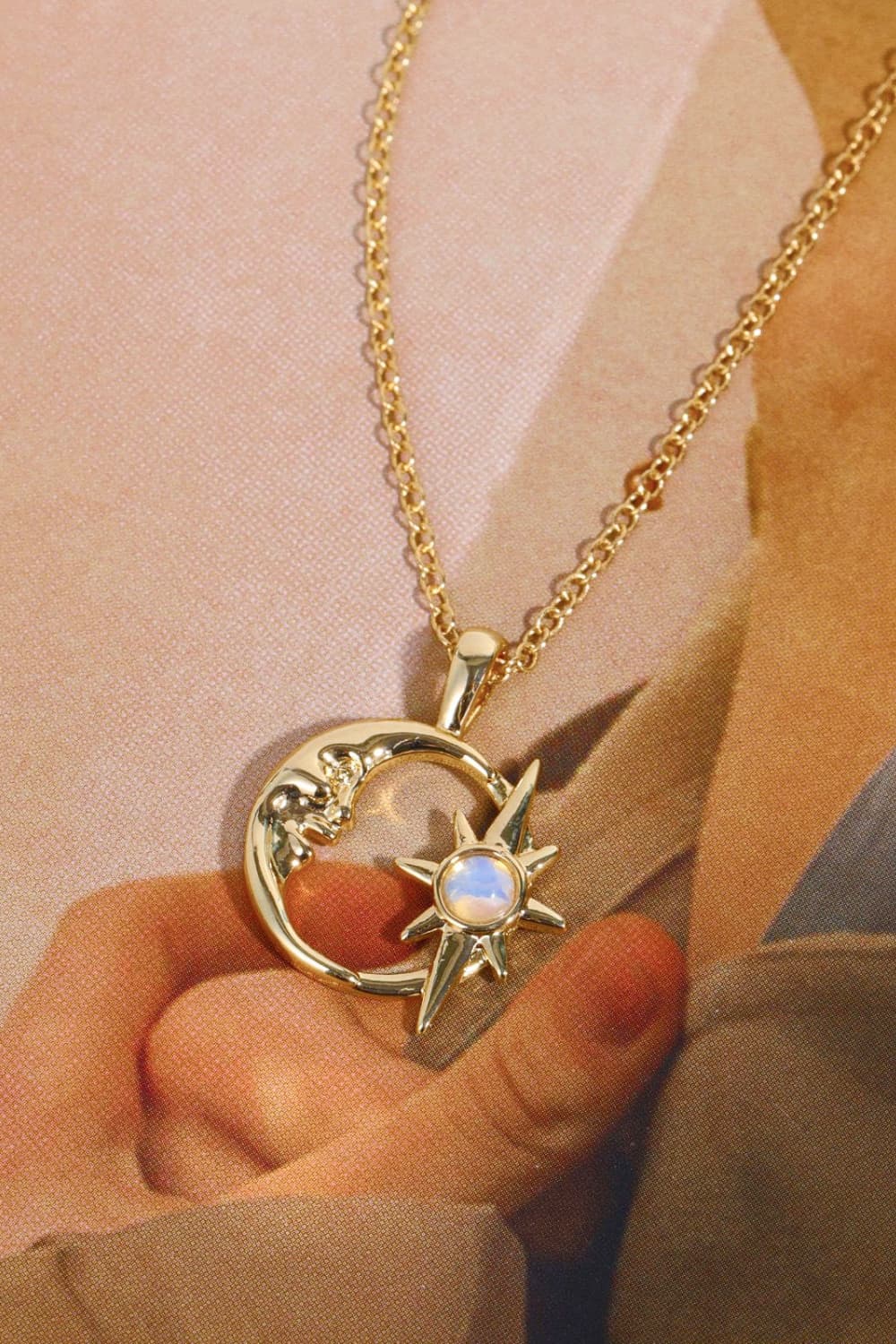 Gold celestial crescent moon and starburst necklace with opal detail.