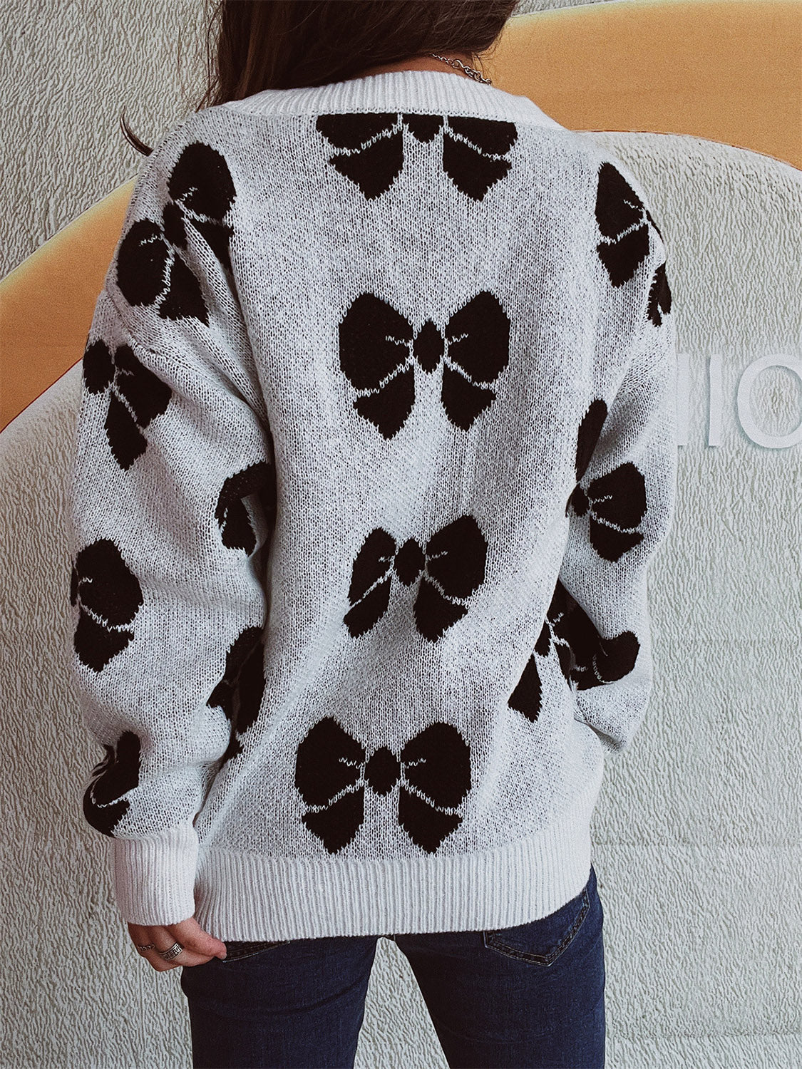 White acrylic sweater with black bow pattern, relaxed fit, crew neck