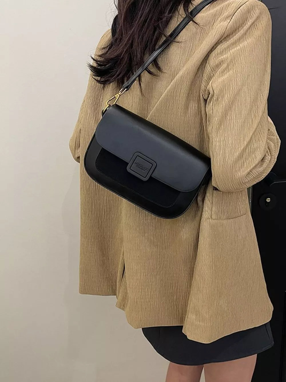 Chic two-tone crossbody bag in black with a textured flap and gold hardware.