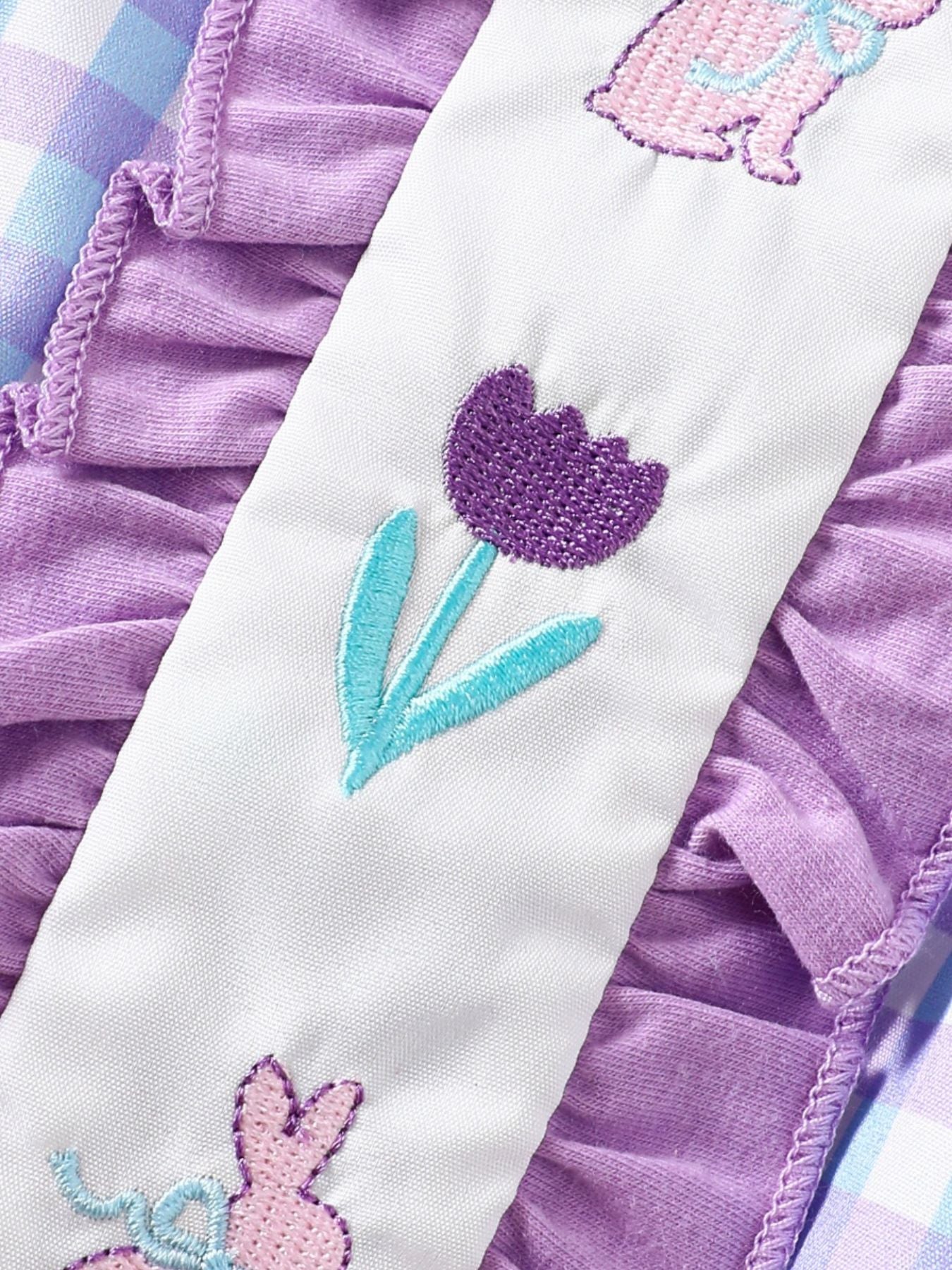 Baby one-piece with purple floral embroidery and ruffled collar in pastel blue and pink purple gingham.