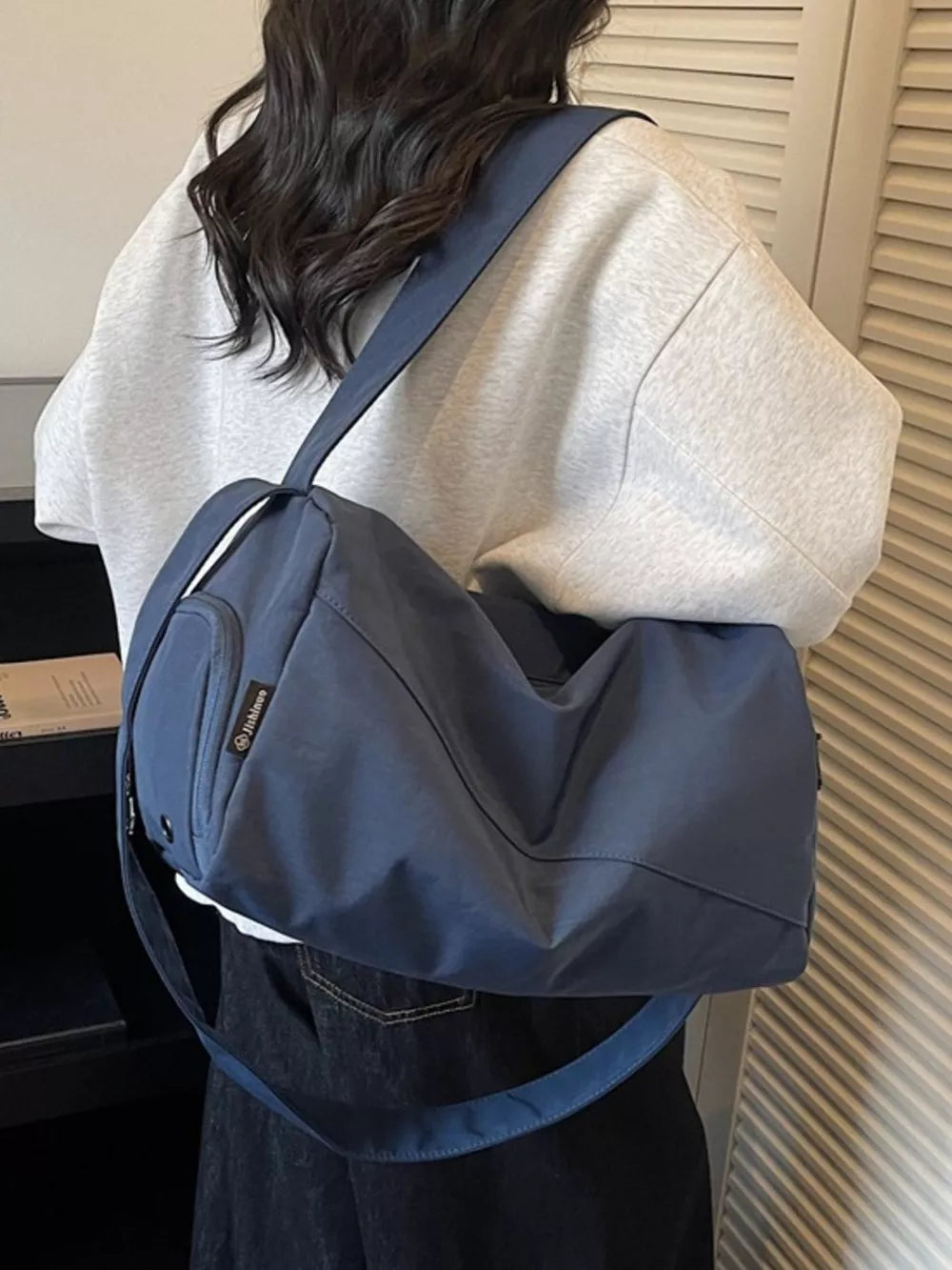 Blue Oxford cloth travel bag with adjustable strap and exterior pocket.