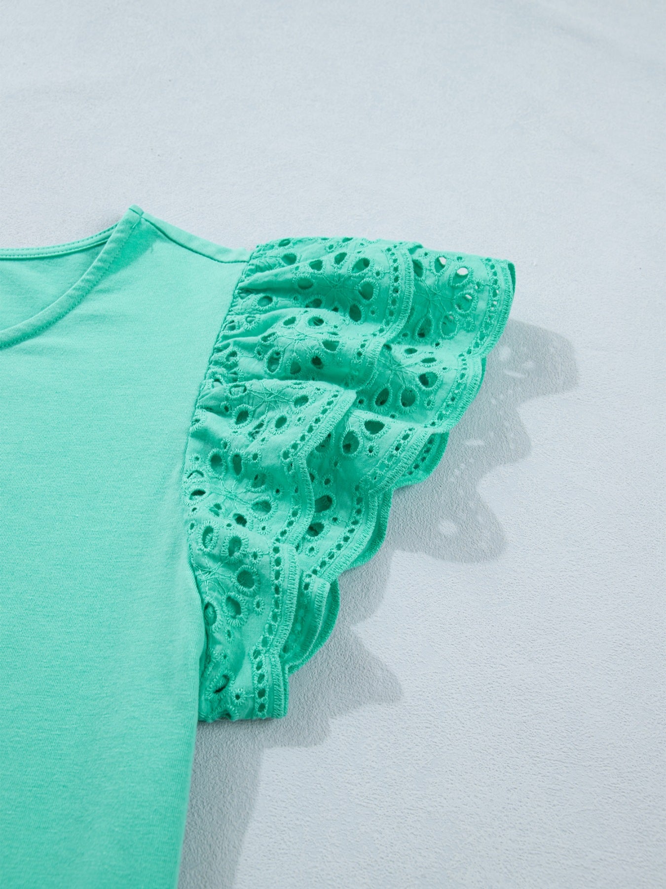 Green eyelet lace ruffled cap sleeve top with scalloped hem detail.