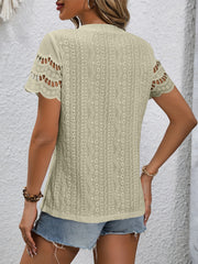 Beige eyelet blouse with scalloped short sleeves and intricate patterned fabric.