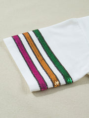 White cotton t-shirt with sequin stripes in pink, gold, and green on the sleeve.