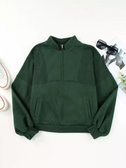 Dark green half zip stand collar sweatshirt with textured panels and front pockets.