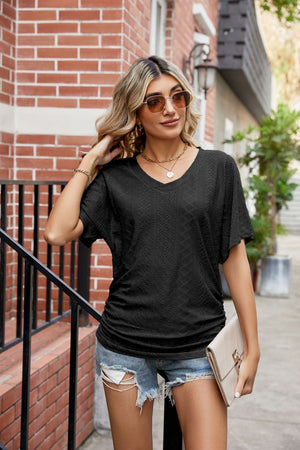 Black perforated dolman sleeve blouse with V-neck and ruching detail.