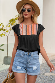 Black blouse with embroidered yoke and ruffle sleeves, styled with denim shorts.