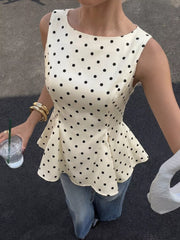 Cream polka dot peplum blouse with a boat neckline and sleeveless design.