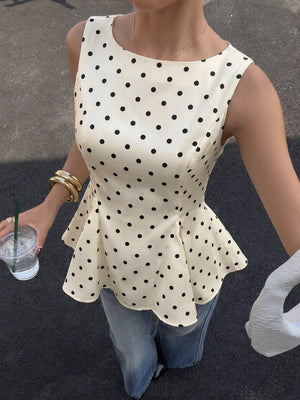 Cream polka dot peplum blouse with a boat neckline and sleeveless design.