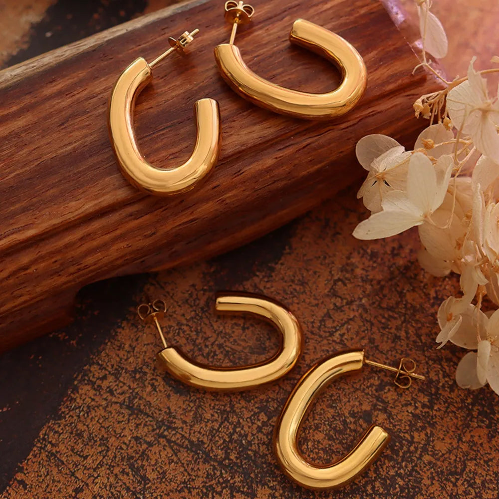 Gold vermeil sculpted hoop earrings with post backs, displayed on a wooden surface.