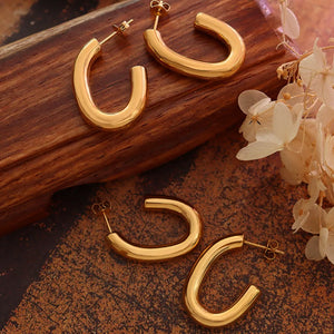 Gold vermeil sculpted hoop earrings with post backs, displayed on a wooden surface.