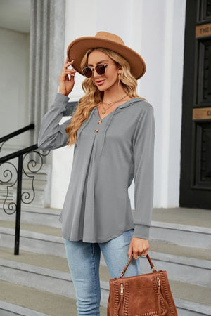 Light gray hooded henley top with button detail and pleats, long sleeves