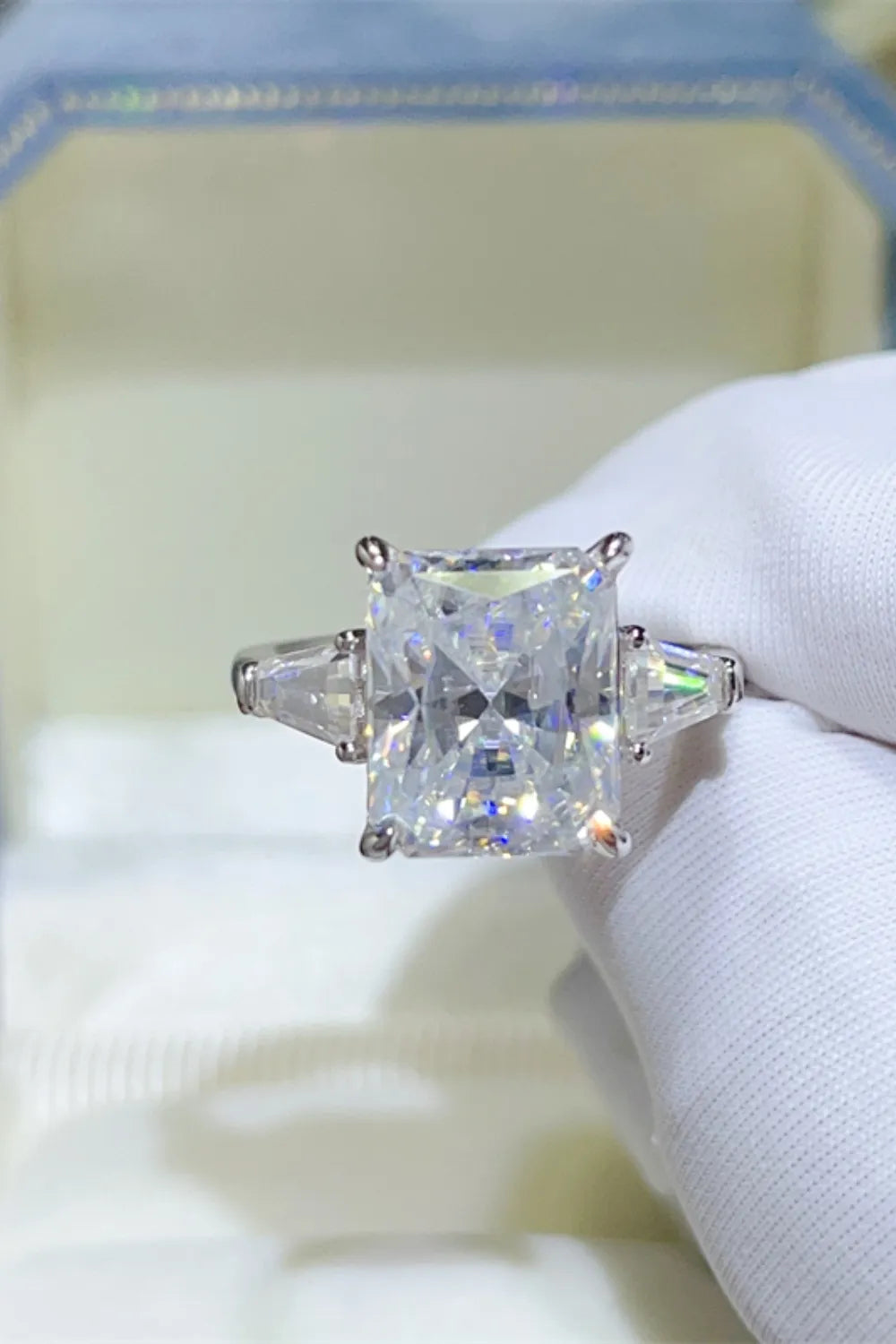 Silver ring with radiant cut moissanite center stone and two baguette side stones.