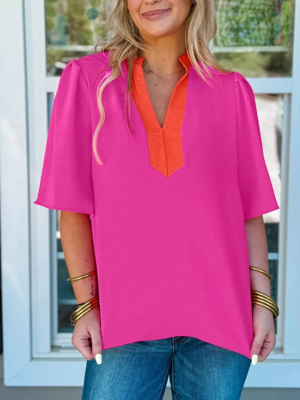 Textured pink blouse with orange V-neck detail and half sleeves.