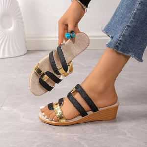 Glistening dual-strap wedge sandals in black and gold with a cork wedge heel.