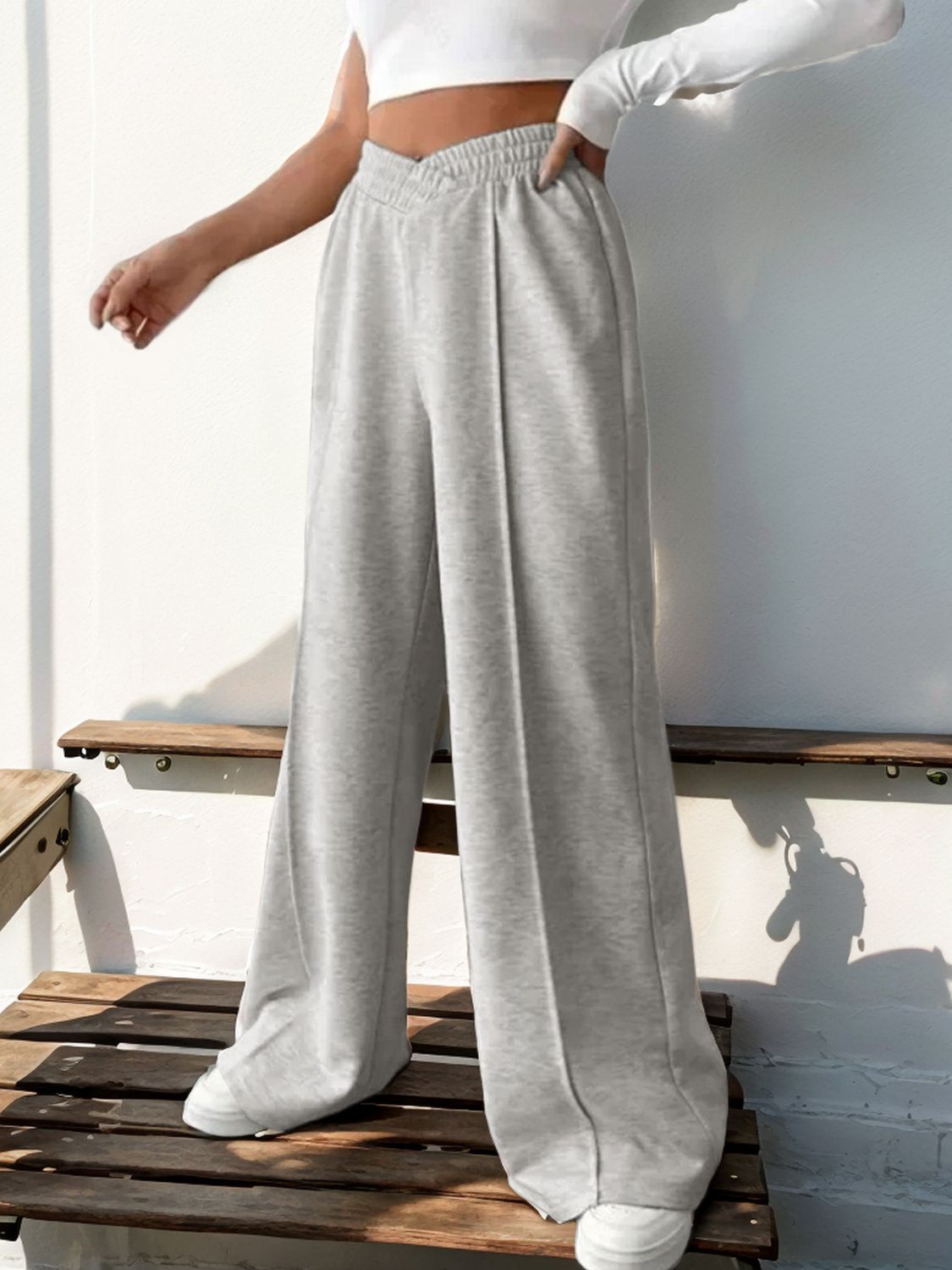 Light gray V-waistline pleated palazzo trousers with a relaxed fit.