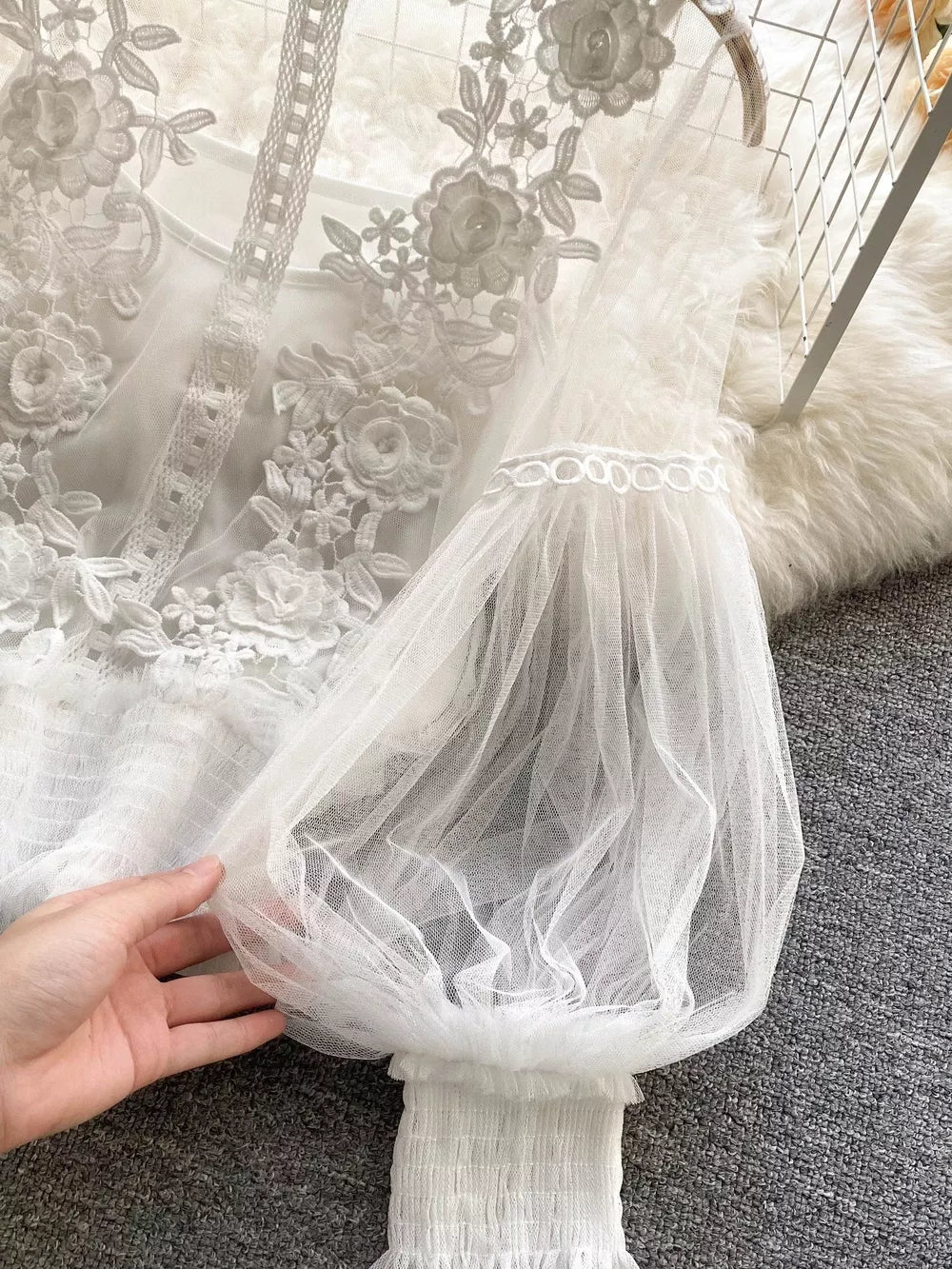 White lace and tulle blouse with embroidered floral details and voluminous sleeves.