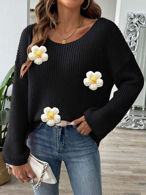 Black slouchy knit sweater with white floral appliqués and a scoop neck.