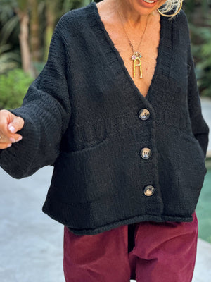 Black textured bouclé oversized button-down cardigan with pockets and V-neck.