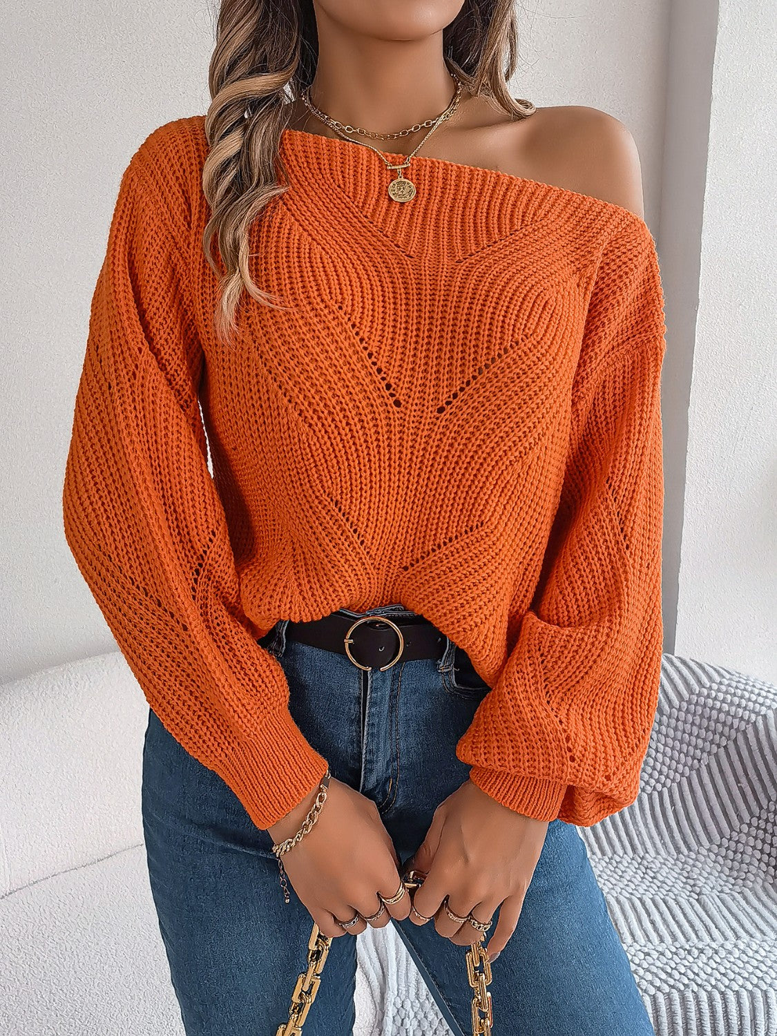 Orange off-the-shoulder knit sweater with openwork detail and long sleeves.