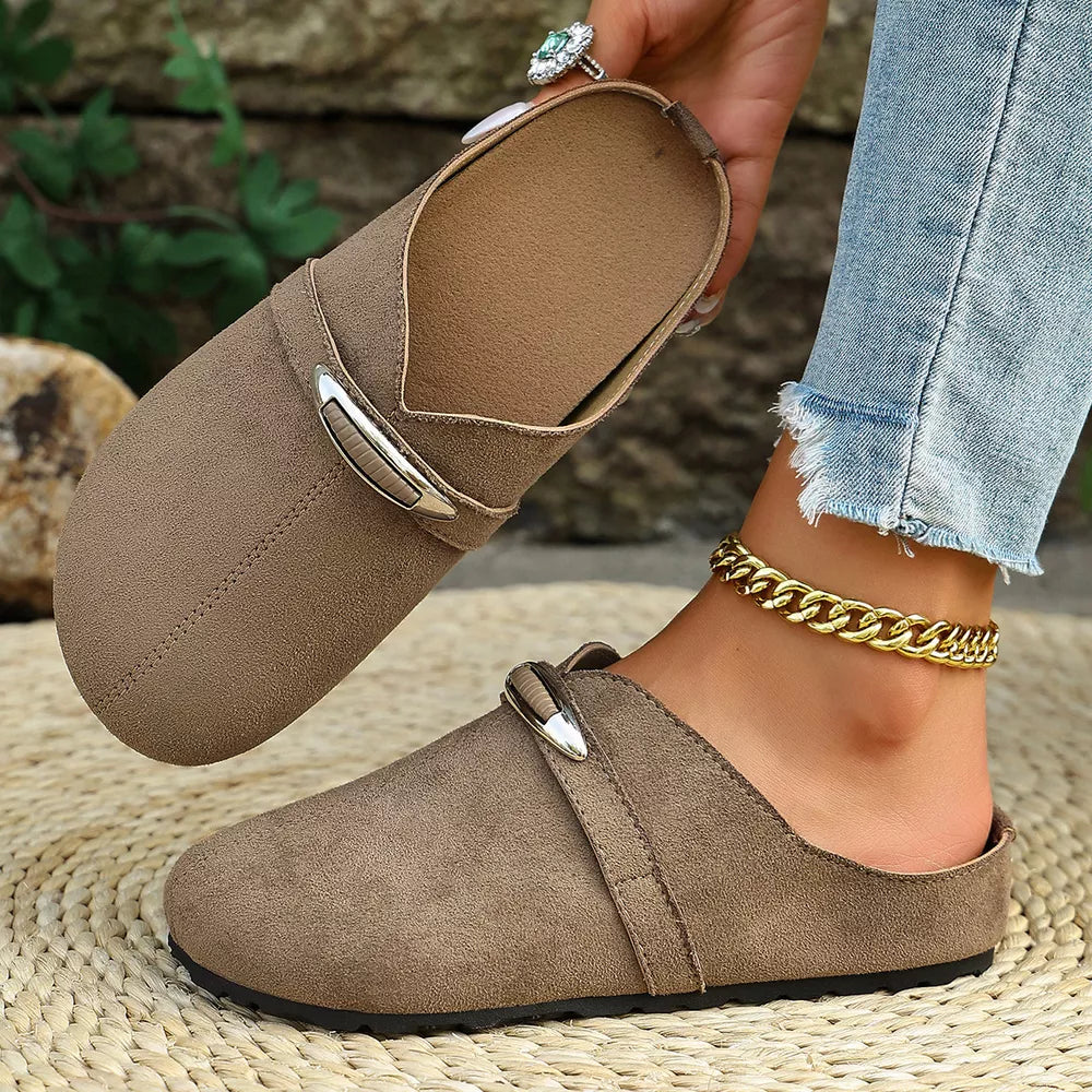 Brown slip-on flats with round toe and decorative buckle detail.