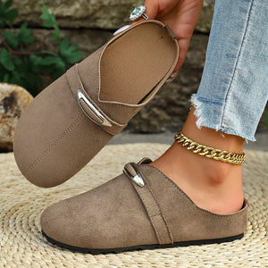 Brown slip-on flats with round toe and decorative buckle detail.