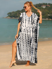 Black tie-dye maxi kaftan with vertical stripes and side slits, worn on the beach.