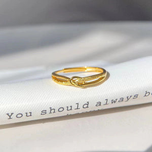 Gold knot ring with textured detail on a white surface with text.
