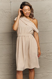 Apricot Swiss dot midi dress with asymmetrical draped neckline and belted waist.