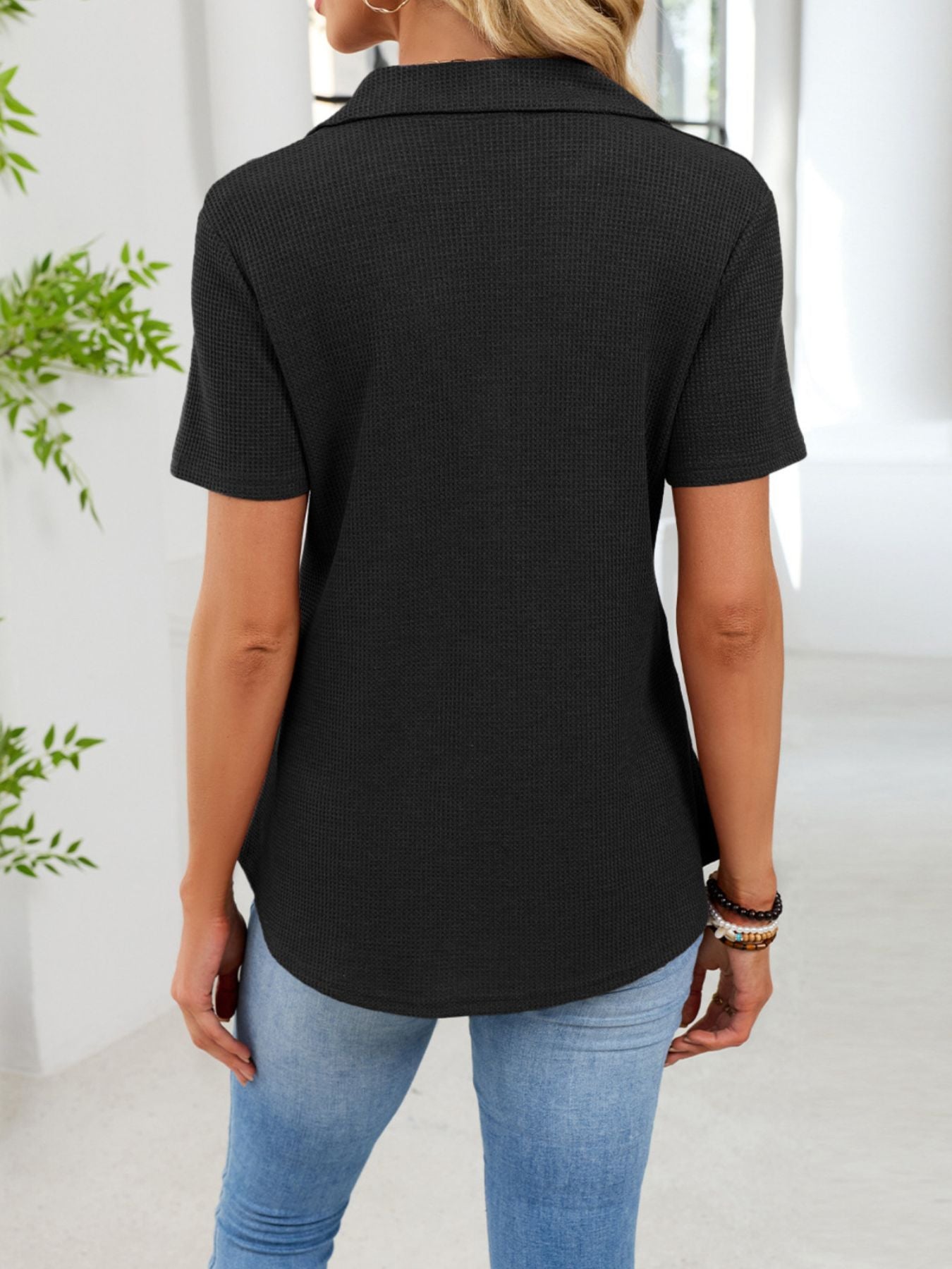 Black waffle knit button placket t-shirt with collared neckline and short sleeves.