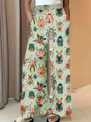 Pastel yellow wide-leg maternity trousers with a colorful beetle print and pockets.