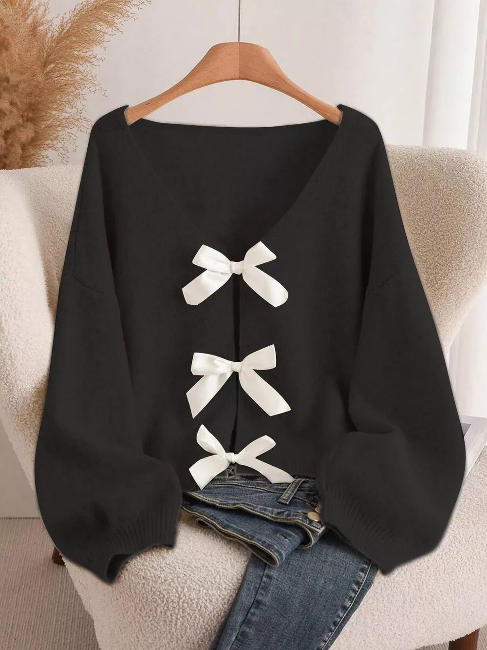 Black V-neck cardigan with balloon sleeves and white bow-knot details down the front.