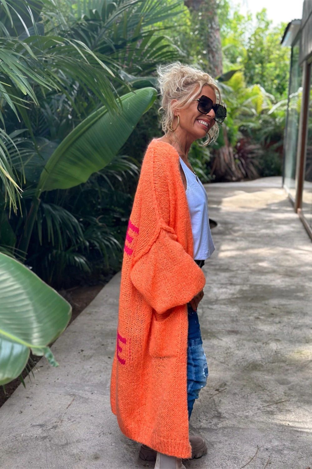 Orange knit maxi cardigan with pink peace sign detail and pockets.