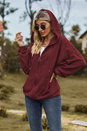 Burgundy textured cable knit zip-up hoodie with a ring pull zipper and pockets.