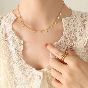 Gold teardrop charm chain necklace with delicate dangling pendants on a fine chain.