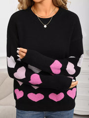 Black crew neck sweater with pink and white heart print on sleeves and hem.