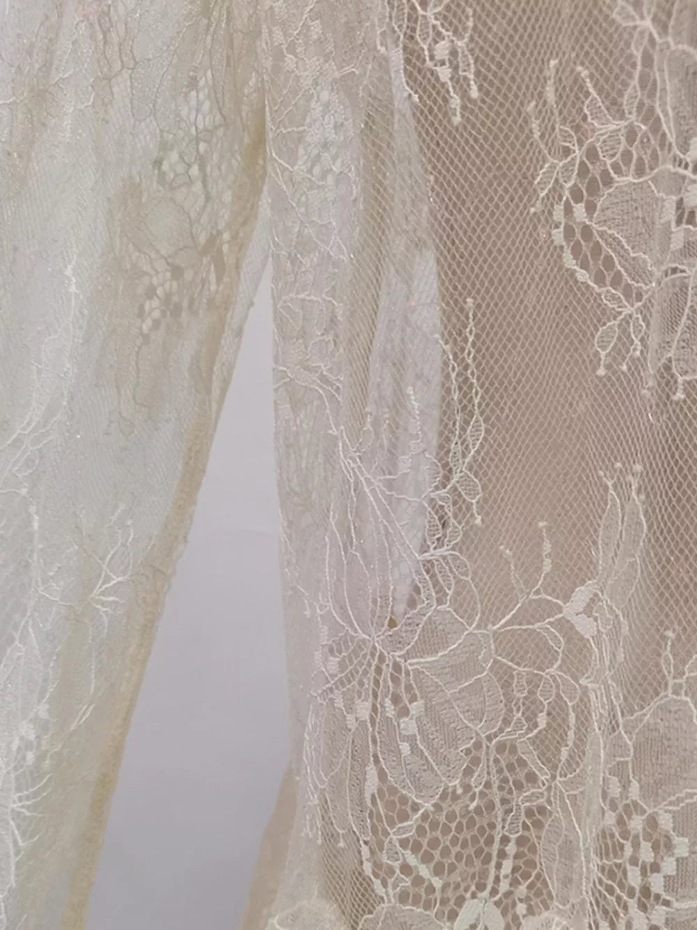 Floral lace dress detail in off-white with intricate floral patterns and a sheer overlay.