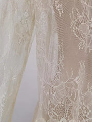 Floral lace dress detail in off-white with intricate floral patterns and a sheer overlay.