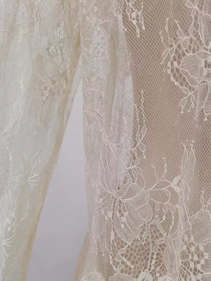 Floral lace dress detail in off-white with intricate floral patterns and a sheer overlay.