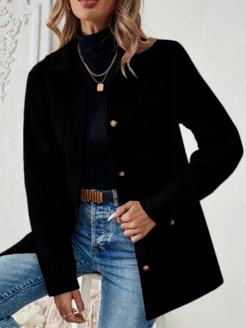 Black button-front trench coat with gold buttons and pockets, styled with jeans.
