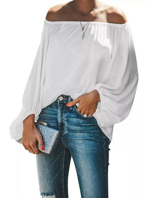 White off-shoulder blouse with balloon sleeves and elastic cuffs, styled with jeans.