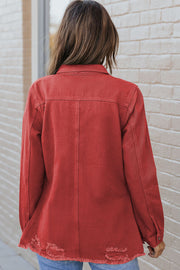 Rust distressed denim shirt jacket with raw edges and button cuffs.