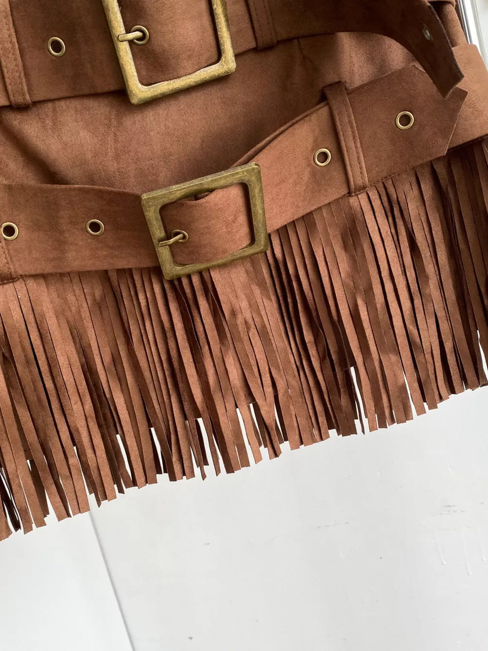Belted mini skirt in brown suede with antique brass buckles and fringe detail.