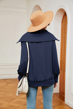 Navy blue wide collar zip-through sweatshirt with balloon sleeves, styled with jeans and a crossbody bag.