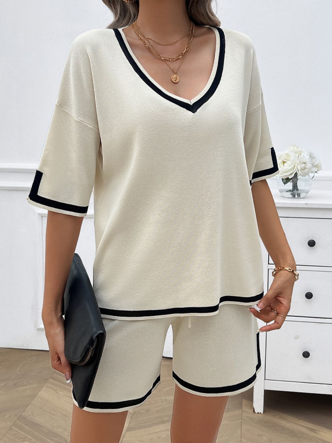 Cream knit lounge set with black contrast trim on v-neck, sleeves, and shorts.
