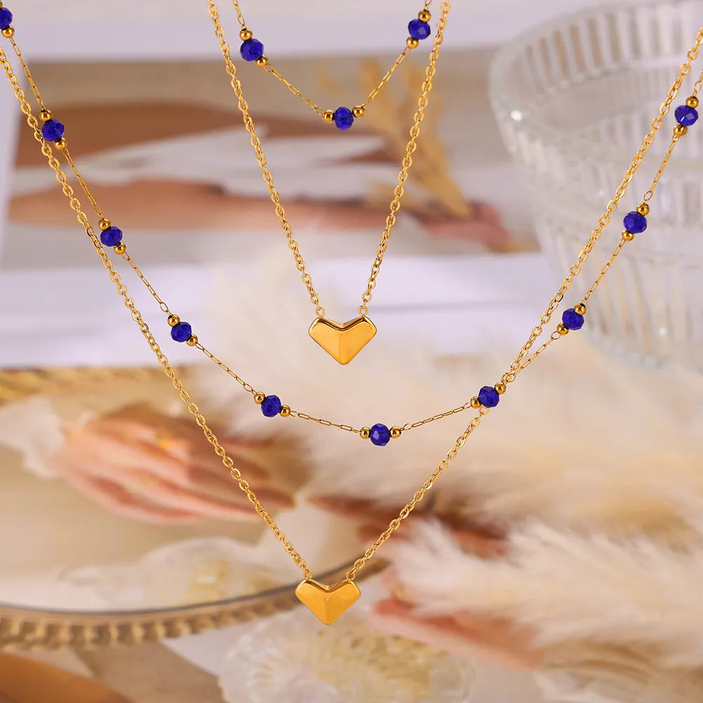 Gold layered necklace with heart pendants and blue beads