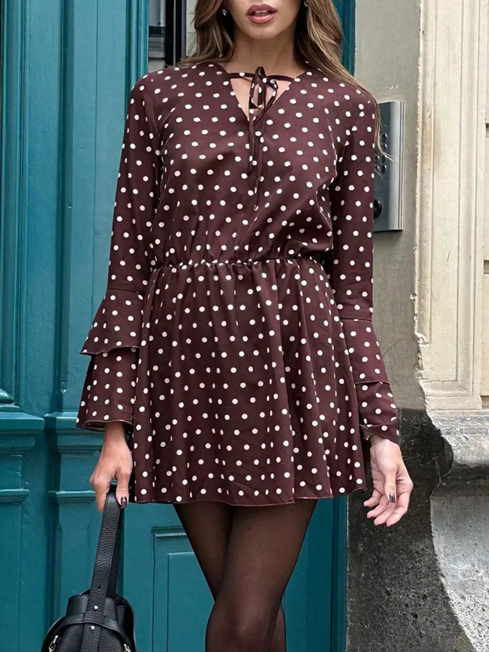 Brown polka dot mini dress with V-neck and tie detail, long sleeves with tiered cuffs.