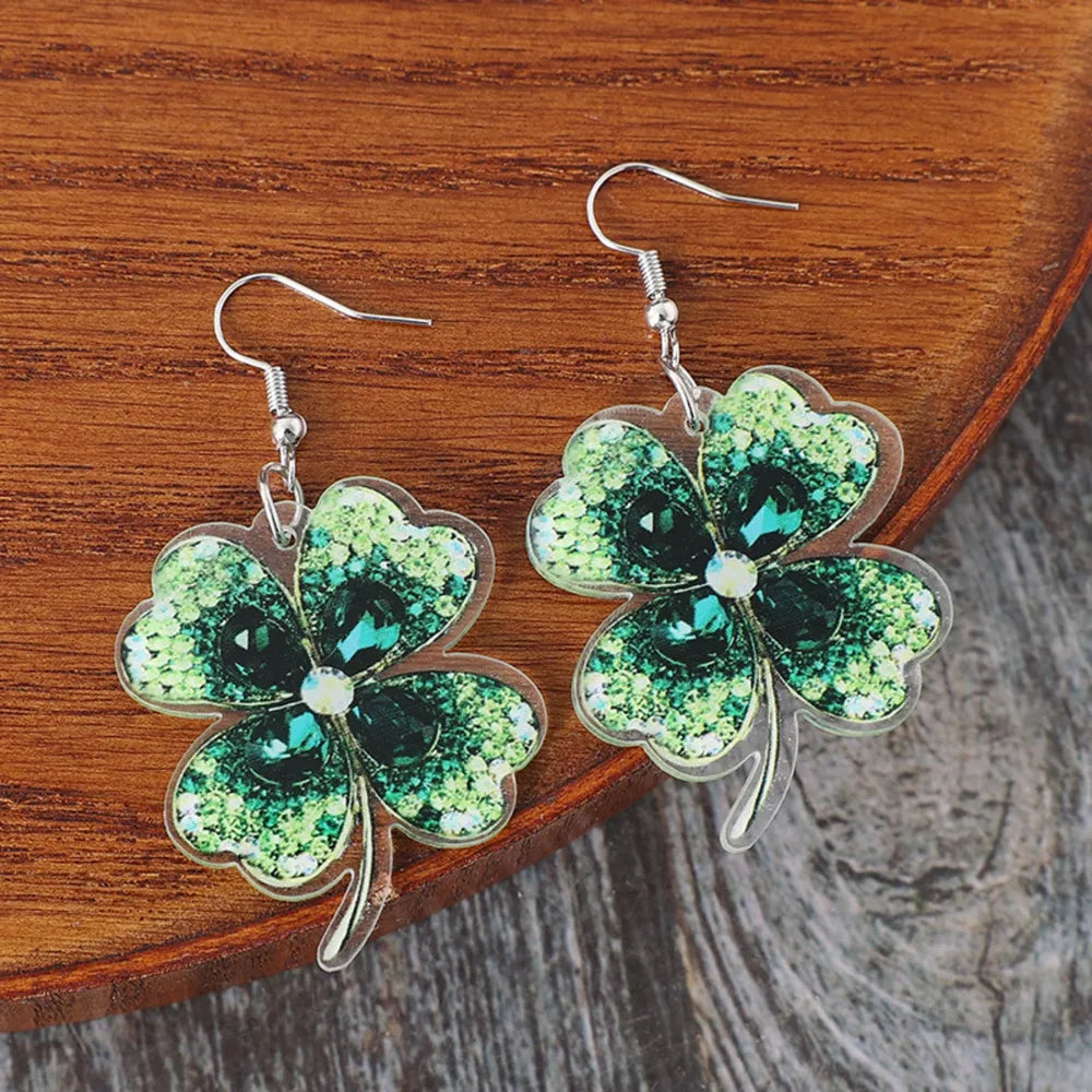 Dark green acrylic clover earrings with gemstone accents and hooks.