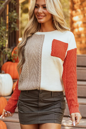 Textured panel sweater with orange pocket and sleeves, cream and tan body, cable knit details.